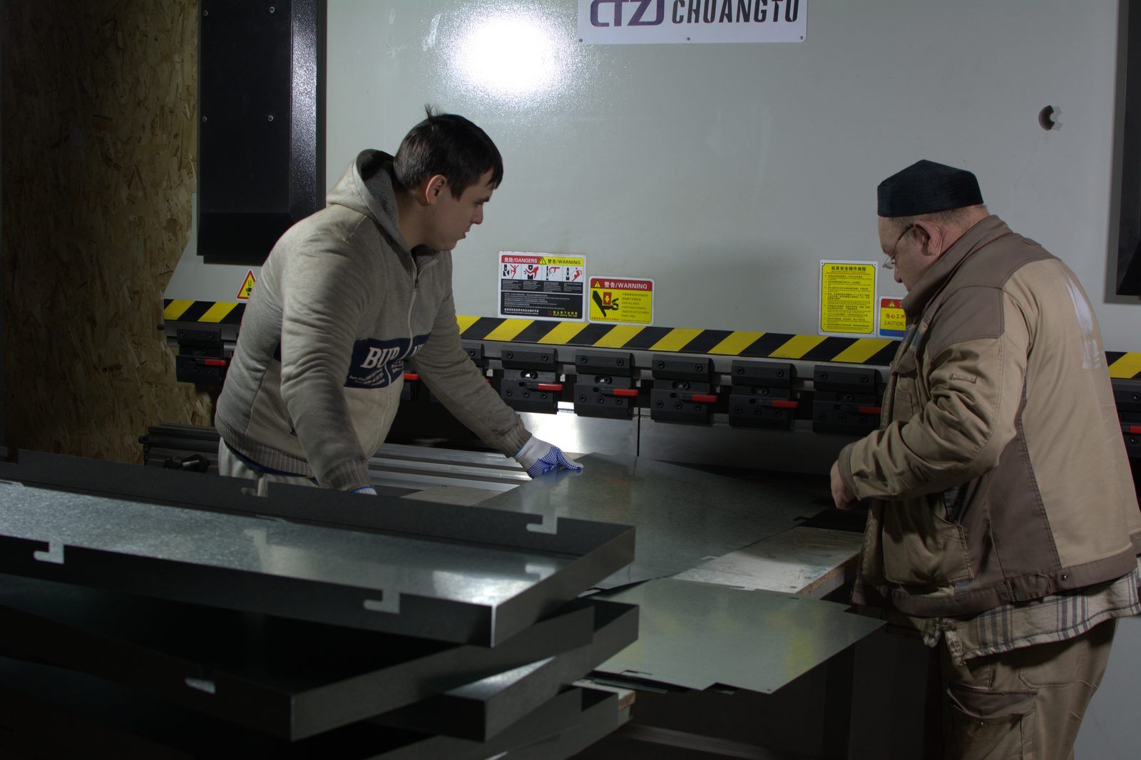 Два оператора формуют лист на листогибочном прессе с ЧПУ